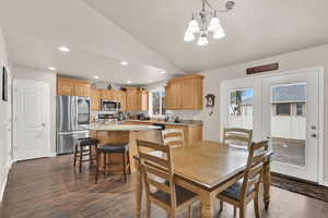 Dining space featuring recessed lighting, dark wood-type flooring, baseboards, vaulted ceiling, and an inviting chandelier