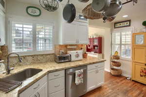 Kitchen with a sink, plenty of natural light, white cabinetry, and dishwasher