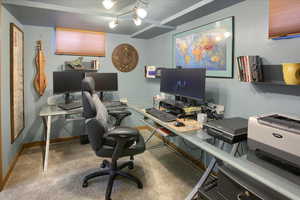 Carpeted office featuring track lighting and baseboards