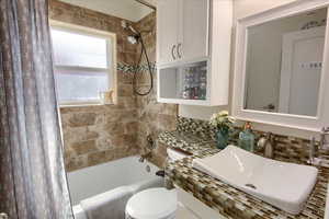 Bathroom with shower / tub combo, a sink, backsplash, and toilet