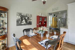 Dining space featuring light wood-type flooring, ceiling fan, and vaulted ceiling