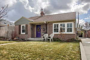 View of front of house with brick siding, fence, a chimney, and a front lawn