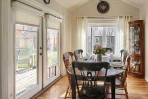 Dining space featuring lofted ceiling, light wood finished floors, and plenty of natural light