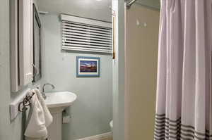 Full bathroom featuring curtained shower, a textured ceiling, and toilet