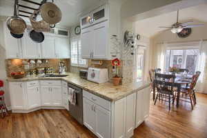 Kitchen with stainless steel dishwasher, decorative backsplash, and white cabinets