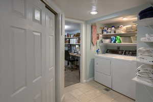 Laundry room featuring laundry area, washing machine and clothes dryer, and light tile patterned floors