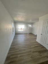 Empty room with a textured ceiling, baseboards, and wood finished floors