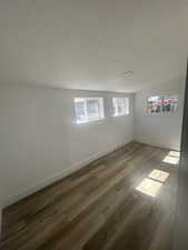 Spare room with a textured ceiling, baseboards, and wood finished floors