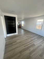 Unfurnished living room with visible vents, a textured ceiling, baseboards, and wood finished floors