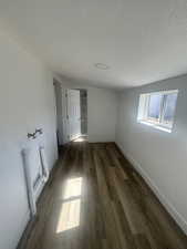 Unfurnished room featuring dark wood-style flooring, a textured ceiling, and baseboards