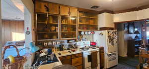 Kitchen with light countertops, white appliances, and brown cabinets