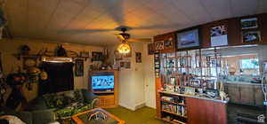 Carpeted living area featuring ceiling fan and baseboards