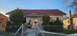 View of front of home with roof with shingles and fence