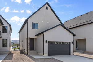 View of front of property featuring a garage, driveway, and central AC