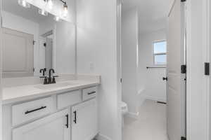 Full bath featuring baseboards, toilet, tile patterned floors, a washtub, and vanity