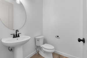 Bathroom with wood finished floors, toilet, and baseboards