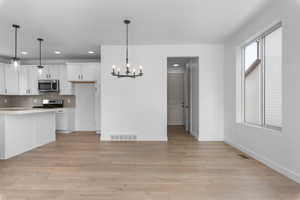 Kitchen featuring stainless steel appliances, light countertops, visible vents, decorative backsplash, and light wood-type flooring
