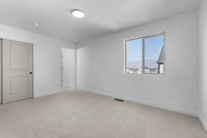 Unfurnished room with baseboards, visible vents, and light colored carpet