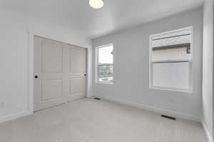 Unfurnished bedroom with carpet, visible vents, and baseboards