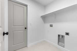 Washroom with laundry area, light tile patterned floors, baseboards, washer hookup, and electric dryer hookup