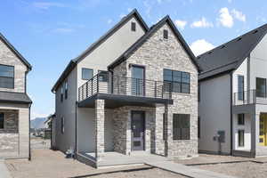 View of front facade with a balcony and stucco siding