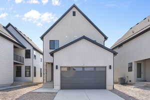 View of front of house featuring a garage, entry steps, central AC, and driveway