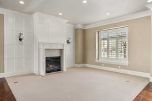 Unfurnished living room featuring ornamental molding, recessed lighting, baseboards, and a fireplace with flush hearth