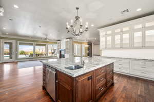 Kitchen with visible vents, stainless steel dishwasher, a kitchen island with sink, white cabinets, and a sink