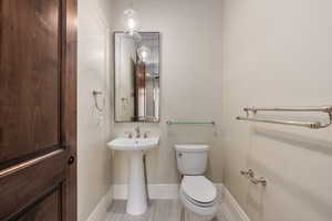 Half bathroom with toilet and baseboards