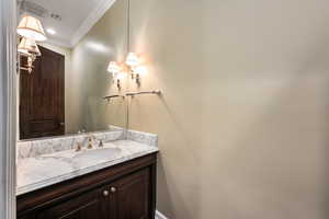 Bathroom featuring visible vents, crown molding, and vanity