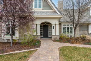 Entrance to property featuring a high end roof, stone siding, and a chimney