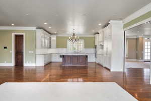 Kitchen with dark wood-style flooring, tasteful backsplash, an island with sink, and plenty of natural light