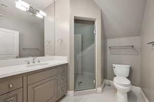 Bathroom featuring visible vents, toilet, vaulted ceiling, vanity, and a shower stall