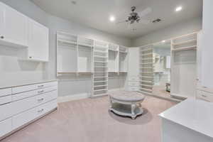 Walk in closet with a ceiling fan, light colored carpet, and visible vents