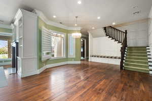 Unfurnished living room with stairs, ornamental molding, wood-type flooring, and visible vents