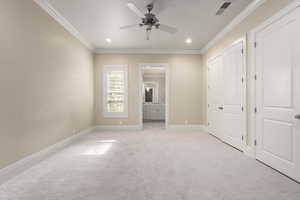 Unfurnished bedroom with light carpet, baseboards, visible vents, ensuite bath, and crown molding