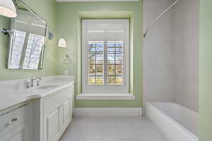 Bathroom featuring tile patterned flooring, vanity, baseboards, and shower / bathtub combination