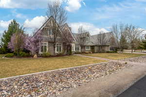 Shingle-style home with stone siding and a front yard