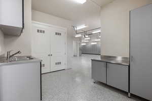 Kitchen with light speckled floor, stainless steel countertops, visible vents, and a sink