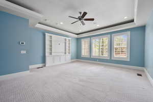 Spare room with visible vents, a tray ceiling, baseboards, and light colored carpet