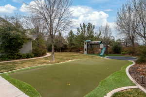 View of community with a playground, a lawn, and fence