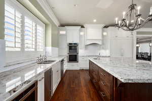 Kitchen with white cabinetry, crown molding, appliances with stainless steel finishes, and a sink