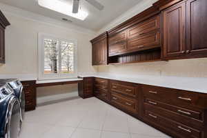 Washroom featuring separate washer and dryer, visible vents, ornamental molding, cabinet space, and wallpapered walls