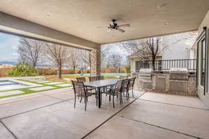 View of patio featuring a ceiling fan, outdoor dining area, a grill, and an outdoor kitchen