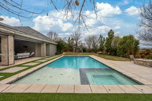 View of pool featuring an outdoor fire pit, a pool with connected hot tub, and a patio