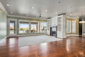 Unfurnished living room featuring crown molding, a fireplace, dark wood-style flooring, and recessed lighting