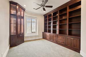 Interior space with baseboards, visible vents, light colored carpet, ceiling fan, and crown molding