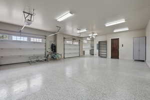 Garage with baseboards, heat pump water heater, and a garage door opener