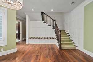 Stairs with baseboards, ornamental molding, a decorative wall, and hardwood / wood-style floors