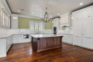 Kitchen with a breakfast bar, dark wood finished floors, glass insert cabinets, and white cabinetry